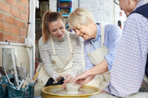 Couple taking a pottery making class with female instructor